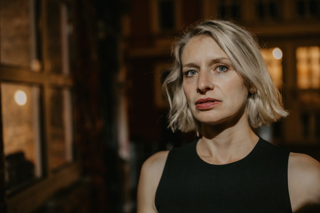 Annika Brönstrup rechts im Vordergrund, schaut direkt, Gesichtszüge ernst, Mund leicht geöffnet